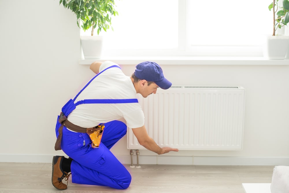 man in blue overalls checking the radiator for boiler efficiency